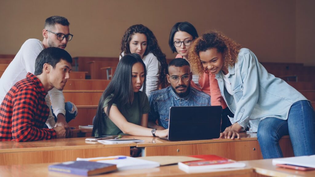 Grupo Diversificado De Estudantes Reunidos Em Torno Do Laptop kp7qkHTgSKc