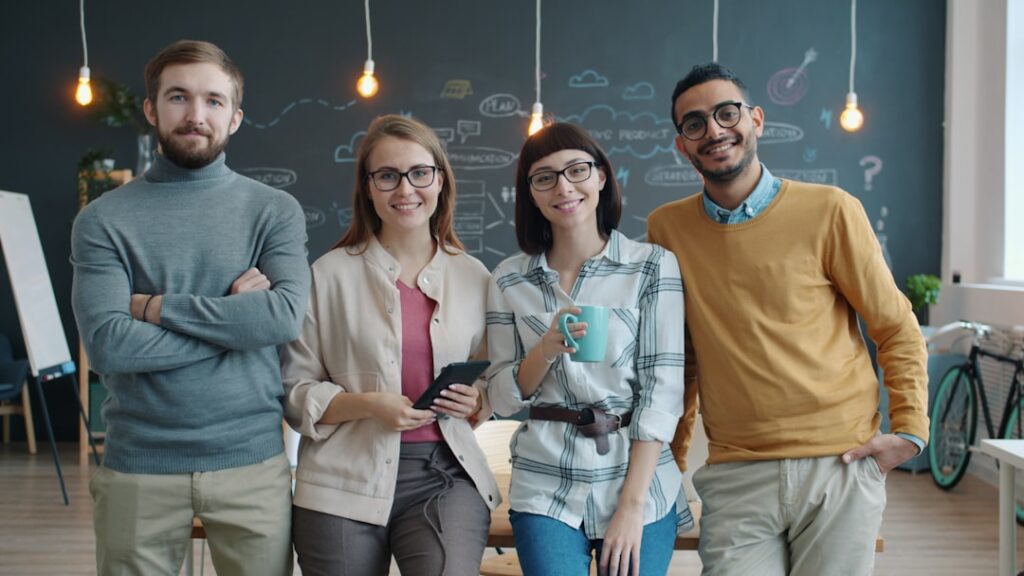 Quatro Pessoas Sorridentes Em Pe Em Um Escritorio Moderno e6rPqzAteII
