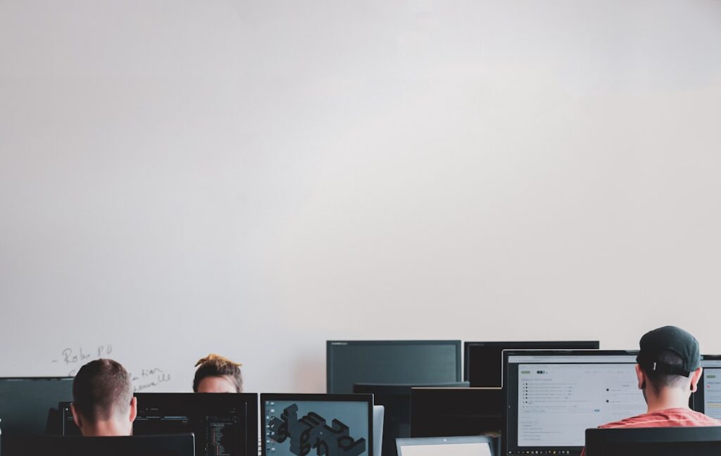 Homem Na Jaqueta Preta Sentado Ao Lado Do Monitor De Computador De Tela Plana Preta rWE7bTqgMJE