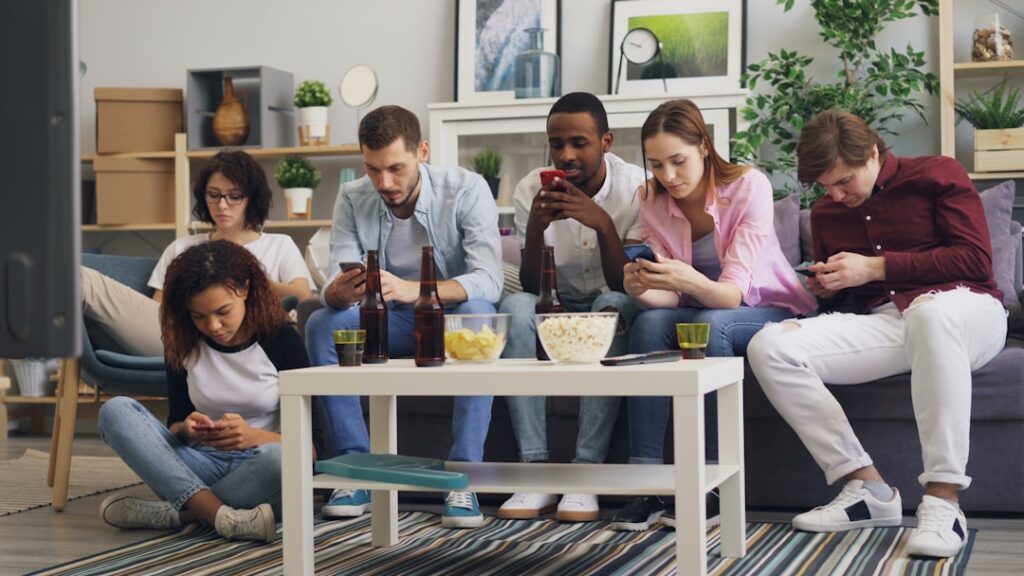 Um Grupo De Pessoas Sentadas Em Um Sofa Olhando Para Seus Telefones MIDlnrHxxyg