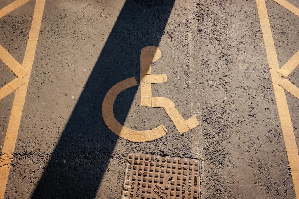 Close-up of a yellow wheelchair symbol painted on asphalt, highlighting accessibility.