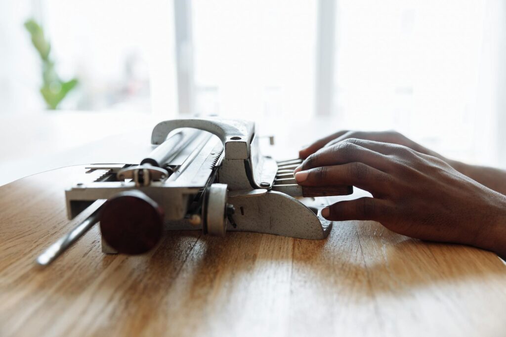 Close-up of hands typing on a braille typewriter, showcasing assistive technology for the visually impaired.