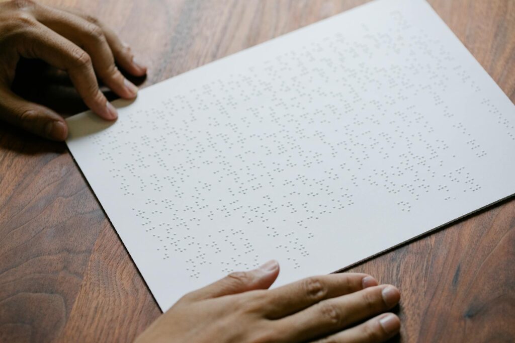 Close-up of hands feeling Braille text on paper, focusing on tactile reading skills.
