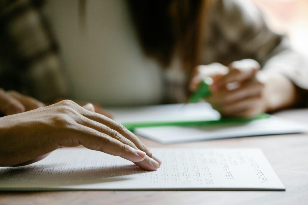 Close-up of hands reading Braille on paper, emphasizing sensory learning and accessibility.