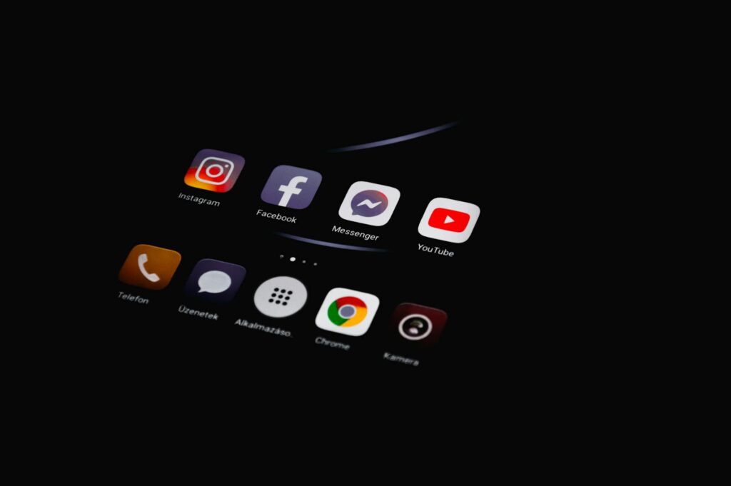 Close-up of smartphone displaying popular social media apps in dim lighting.